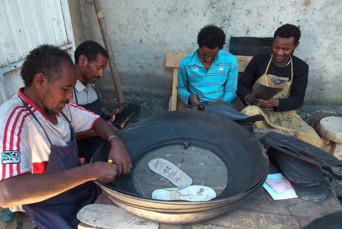 Workers cut shoe designs from discarded tyres